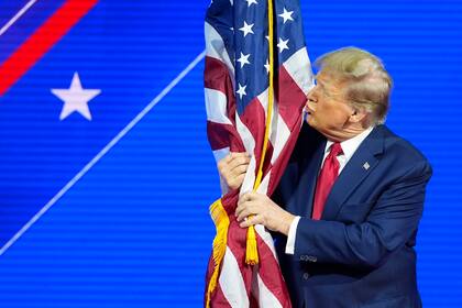El candidato presidencial republicano, el expresidente Donald Trump, abraza y besa la bandera estadounidense mientras habla en la Conferencia de Acción Política Conservadora, CPAC 2024, en National Harbor, en Oxon Hill, Maryland, el sábado 24 de febrero de 2024.