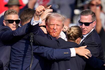 El candidato republicano a la presidencia Donald Trump alza el puño mientras recibe ayuda para salir del escenario en un acto de campaña en Butler, Pensilvania, el sábado 13 de julio de 2024. (AP Foto/Gene J. Puskar)