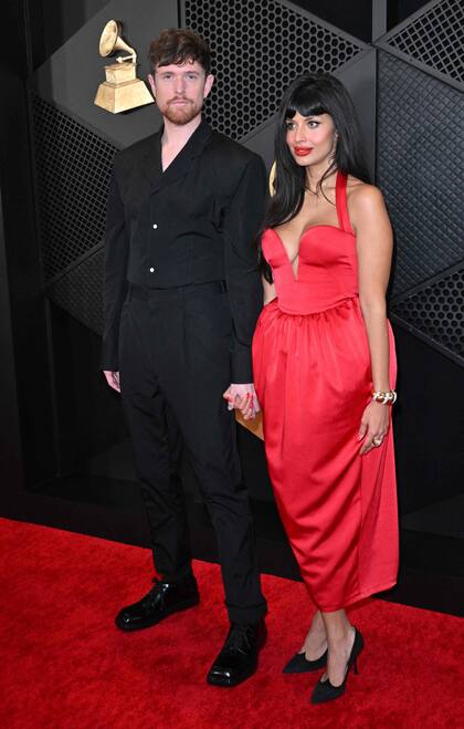 El cantante británico James Blake y su pareja, la actriz Jameela Jamil, con un vestido rojo con breteles, de escote corazón y falda bombé