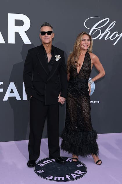 El cantante británico Robbie Williams y su pareja, la influencer estadounidense Ayda Field, concurrieron a la cita totalmente engamados: él, con un traje negro cruzado y camisa también negra, y ella con un revelador vestido del mismo color, con pronunciado escote, transparencias y detalle de plumas en la parte inferior