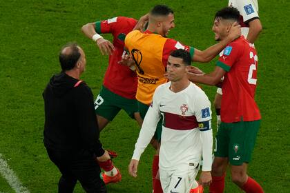 El capitán de Portugal, Cristiano Ronaldo, deja el campo mientras los jugadores de Marruecos celebran tras la victoria 1-0 por los cuartos de final del Mundial en el estadio Al Thumama de Doha, Qatar, sábado 10 de diciembre, 2022. (AP Foto/Alessandra Tarantino)