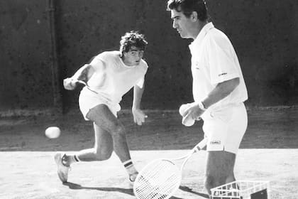 Guillermo Pérez Roldán pega un revés, bajo la mirada de Raúl, durante una pretemporada en Tandil en los 80