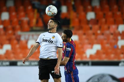 El centrocampista español del Valencia Carlos Soler (L) compite con el centrocampista español del Barcelona Sergio Busquets durante el partido de fútbol de la Liga española entre Valencia y Barcelona en el estadio Mestalla de Valencia el 2 de mayo de 2021.
