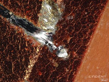 El chasis de aluminio aparece debajo de la pintura naranja en un iPhone 17 Pro; la marca se hizo con una moneda