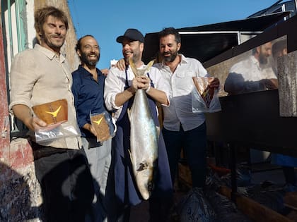 El chef Gabriel Oggero, de Crizia, levanta un pez limón junto a los hermanos Matías y Facundo Bernatene y al productor Agustín Benito