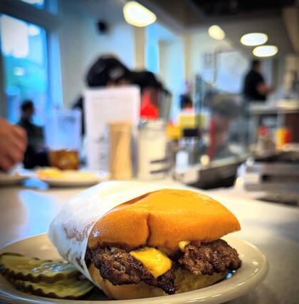 El chef recomienda acompañar la hamburguesa con una lámina de queso fundido, pan de papa tostado, una capa de mayonesa y un par de rodajas de pepinillos
