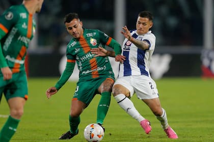 El chileno Cristopher Mesias disputa la pelota con Alex Vigo; el lateral de Talleres es uno de los futbolistas que tuvieron acción en medio de la rotación que impuso el entrenador Walter Ribonetto