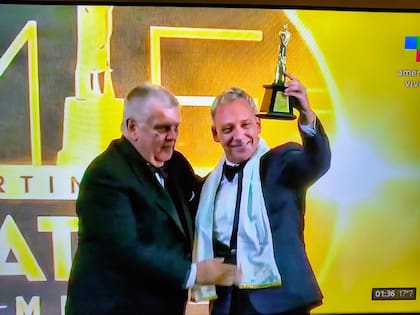 El chileno Martín Cárcamo, con la chalina de Cacho Rubio, recibe el Martín Fierro Latino de Oro de manos de Luis Ventura, presidente de APTRA