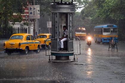 Un agente de tránsito se resguarda durante las fuertes lluvias, en Kolkata