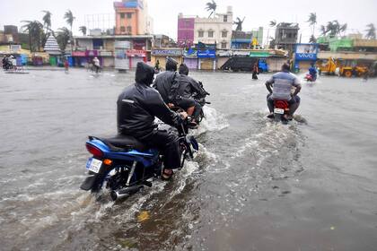 Residentes cruzan en motocicleta por una carretera inundada después de que el ciclón Fani tocó tierra en Puri, en el estado indio oriental de Odisha