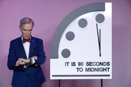 El científico Bill Nye, mira su reloj junto al Reloj del Juicio Final, poco antes de que el Boletín de Científicos Atómicos anuncie la última decisión. Este año, enero de 2024, el reloj permanecerá ajustado a 90 segundos para la medianoche.(AP/Jacquelyn Martin)�