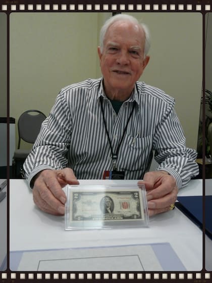 El comandante del Apolo 15 y el caminante lunar David Scott sosteniendo el billete de $ 2 volado en la reunión de la Fundación de Becas de Astronautas en noviembre de 2008, por Jefferson Space Museum