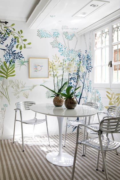 El comedor diario, pasos antes de la cocina, alegrado por un mural de Lu Garabello. Tiene una mesa ‘Tulip’ blanca rodeada por sillas ‘Toledo’, del diseñador argentino Jorge Pensi (1946-2025)