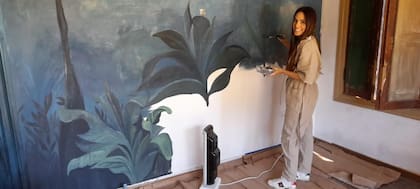 El comienzo. Parte de la pared aún en blanco, Florencia comienza a pintar el fondo de su obra.