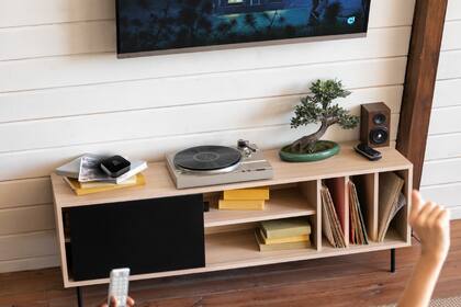 El control remoto universal de Positivo (en la imagen, a la izquierda del tocadisco) permite controlar dispositivos vía infrarrojo, wi-fi y Bluetooth