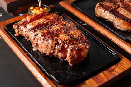 El corazón de la carta late en cortes de Angus Black—bife de chorizo, asado banderita y entraña—madurados al vacío y cocinados sobre brasas de quebracho colorado, y se amplía con apuestas como el T-Bone y el ojo de bife de Wagyu