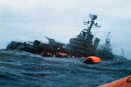 La imagen del Crucero General Belgrano en el momento en el que está por sumergirse por completo. Al lado, las balsas en las que parte de la tripulación pudo escapar 