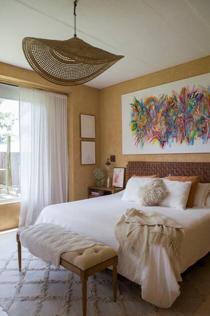 El cuadro de María Santi (Praxis) se acompañó con un respaldo de cuero trenzado y una luminaria de yute (Rancho Deco).