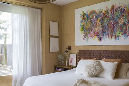 El cuadro de María Santi (Praxis) se acompañó con un respaldo de cuero trenzado y una luminaria de yute (Rancho Deco).