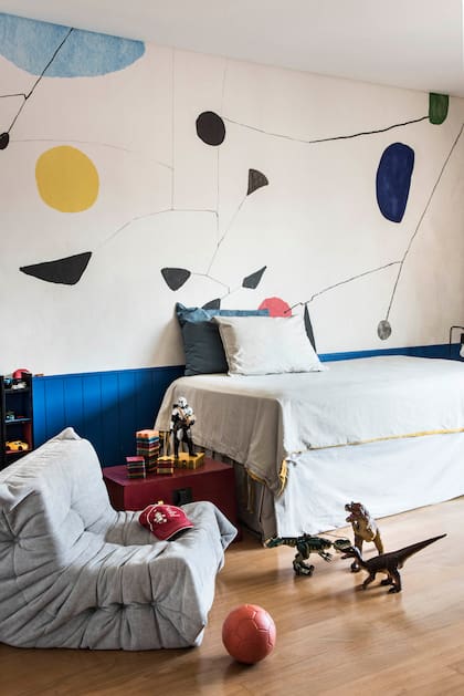 El cuarto del menor de la familia tiene un revestimiento perimetral varillado en laca azul, empapelado ‘Calder’ (Edición Particular) y sillón ‘Togo’ (Manifesto).