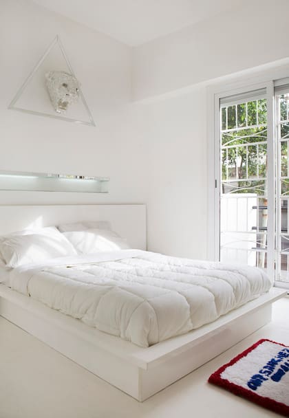 El cuarto es blanco y por demás minimalista. Los muebles de la cama y mesas de luz fueron diseño de él, igual que la cabeza de tigre y la alfombra.