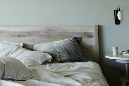 El cuarto principal en el primer piso, con cama de madera y mesita regulable (todo, de Canvas Home). Almohadas batik (Kirsten Hektermann) y lámpara 'Scorpion' (Ochre).