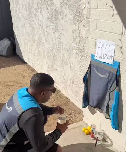 El cubano aparece arrodillado frente a una ofrenda en el suelo, con una chaqueta de la empresa pegada en la pared junto a un cartel que dice “San Amazon”