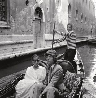 Él, de traje y boina,
y ella, con una capa
blanca y anteojos de sol,
disfrutando de un paseo
en góndola por Venecia
durante su luna de miel.