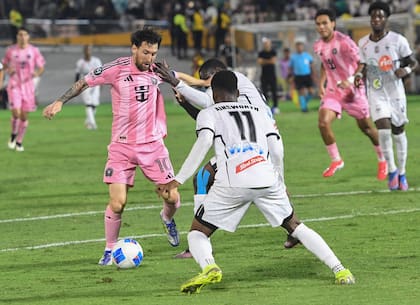 El delantero de Inter Miami Lionel Messi, a la izquierda, intenta quitarle el balón a Christopher Ainsworth, del Cavalier de Jamaica, durante un partido de fútbol de la Copa de Campeones de la CONCACAF en Kingston, Jamaica
