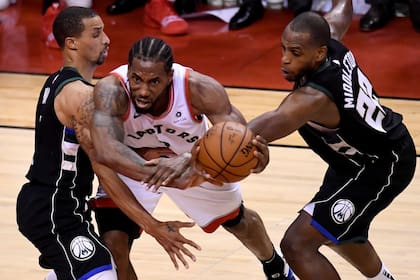 El delantero de los Toronto Raptors, Kawhi Leonard (2), trabaja entre George Hill, de Milwaukee Bucks, a la izquierda, y Khris Middleton (22) durante la segunda mitad del Juego 6 de las finales de la Conferencia del Este de la NBA el sábado 25 de mayo de 2019 en Toronto.