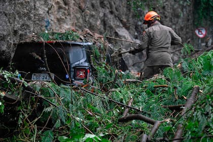Un rescatista trabaja en la recuperación de un automóvil luego de un deslizamiento de tierra provocado por fuertes lluvias y que afectó a la ciudad desde la noche de ayer, inundando varias áreas de la ciudad de Río de Janeiro, en Brasil