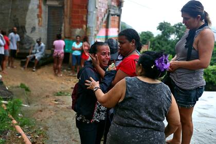 Familiares de una persona desaparecida lloran en el sitio de un alud después de las fuertes lluvias, en el barrio de Babilonia