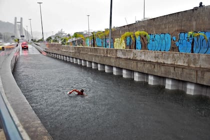 Un bombero de la unidad submarina se zambulle para inspeccionar un automóvil sumergido en un túnel de carretera, después de las fuertes lluvias