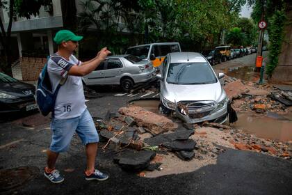  Un hombre toma una fotografía cerca de un automóvil dañado luego de fuertes lluvias en el barrio Jardim Botanico en Río de Janeiro