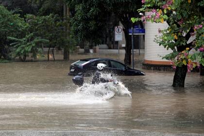  Un hombre maneja su motocicleta durante las inundaciones después de las fuertes lluvias en el barrio de Humaita, Río de Janeiro