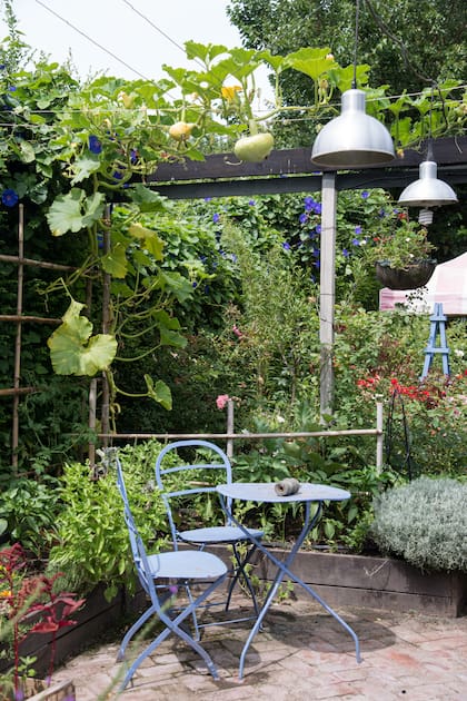 El detalle de repetir el color en el mobiliario exterior y las estructuras de apoyo de las plantas enriquece el diseño en un jardín comestible.