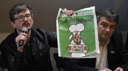 El dibujante Riss (izquierda) sostiene la edición de Charlie Hebdo que fue publicada luego del ataque terrorista que mató 12 de sus trabajadores, durante una conferencia de prensa en 2015