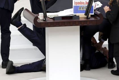 El diputado del Partido de la Felicidad (Saadet) Hasan Bitmez (C) yace en el suelo tras desplomarse mientras pronunciaba su discurso sobre el presupuesto del Ministerio de Justicia y del Ministerio del Interior para 2024, en la Gran Asamblea Nacional Turca (TBMM) en Ankara el 12 de diciembre de 2023. (Foto de Adem ALTAN / AFP)