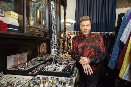 El diseñador con sus tesoros. En sus manos muestra los anillos de calavera que combinan con la estampa de su camisa.