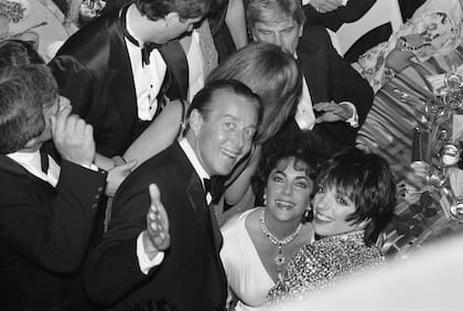 El diseñador de moda Halston, la actriz Elizabeth Taylor y la cantante y actriz Liza Minnelli sonríen en la fiesta de la noche de inauguración de la reposición de Broadway de The Little Foxes