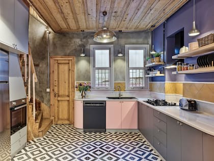 El diseño geométrico de los pisos calcáreos se suaviza con los muebles bajomesada laqueados en gris y rosa.