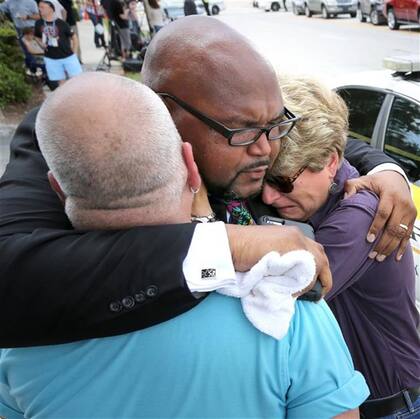 El dolor: un religioso consuela a una funcionaria del gobierno de Orlando y a un abogado de los derechos de los gays