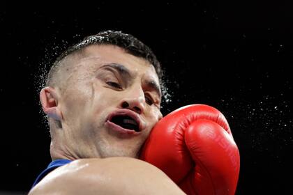 El dominicano Emiliano Rohan Polanco, recibe una golpe de Bobo-Usmon Baturov, de Uzbekistan en la competencia de boxeo