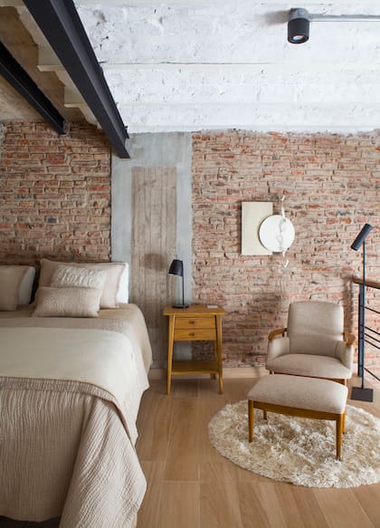 El dormitorio, en el entrepiso, respeta sigue la paleta neutra de la planta baja. Mesa de luz (Bacano) y sillón (Lu Picco). Escultura (colectivo Creta Caliza).