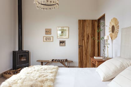 El dormitorio principal de la misma casa. Junto a la salamandra, canasto de rama de poleo, una artesanía exclusiva de la provincia. Sobre el banco rústico, ponchos del tejedor Luis Choque.