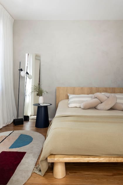 El dormitorio revestido con ‘Estuco Veneciano’ (Tarquini) tiene respaldo a medida (Simple Arquitectos), cama con patas torneadas (Yūgen), almohadón ‘Nudop’ (Naz), mesita metálica (Cúmulo), lámpara de pie (Ikea) y alfombra (Hebra).