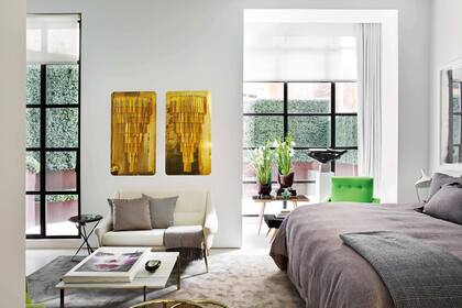 El dormitorio tiene una zona de estar con díptico de cristales de Paolo Venini montados sobre placas metálicas. Sillón francés de los años 50 y mesa ‘PK61’, del diseñador danés Poul Kjaerholm.