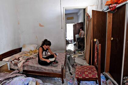 Una mujer limpia los escombros de su casa dañada en la capital libanesa, Beirut