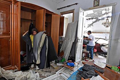 Una mujer inspecciona sus pertenencias en su casa dañada en la capital libanesa, Beirut