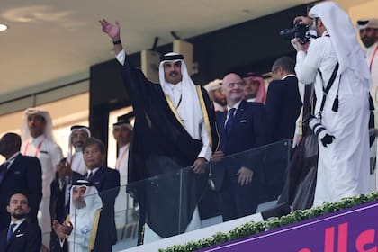 El emir jeque de Qatar, Tamim bin Hamad al-Thani, saluda a la multitud cuando llega con el presidente de la FIFA, Gianni Infantino, para el partido de fútbol del Grupo A de la Copa Mundial de Qatar 2022 entre Qatar y Ecuador en el estadio Al-Bayt